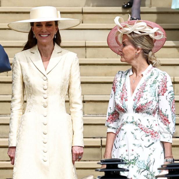 Catherine, Prinzessin von Wales, und Herzogin Sophie stehen in festlicher Kleidung und mit Hüten auf einer Treppe.